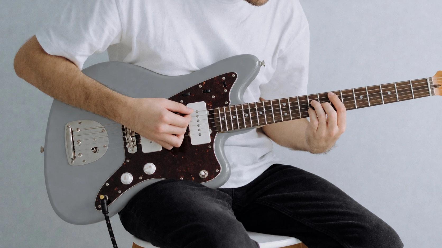 Close-up of a musician playing a grey electric guitar